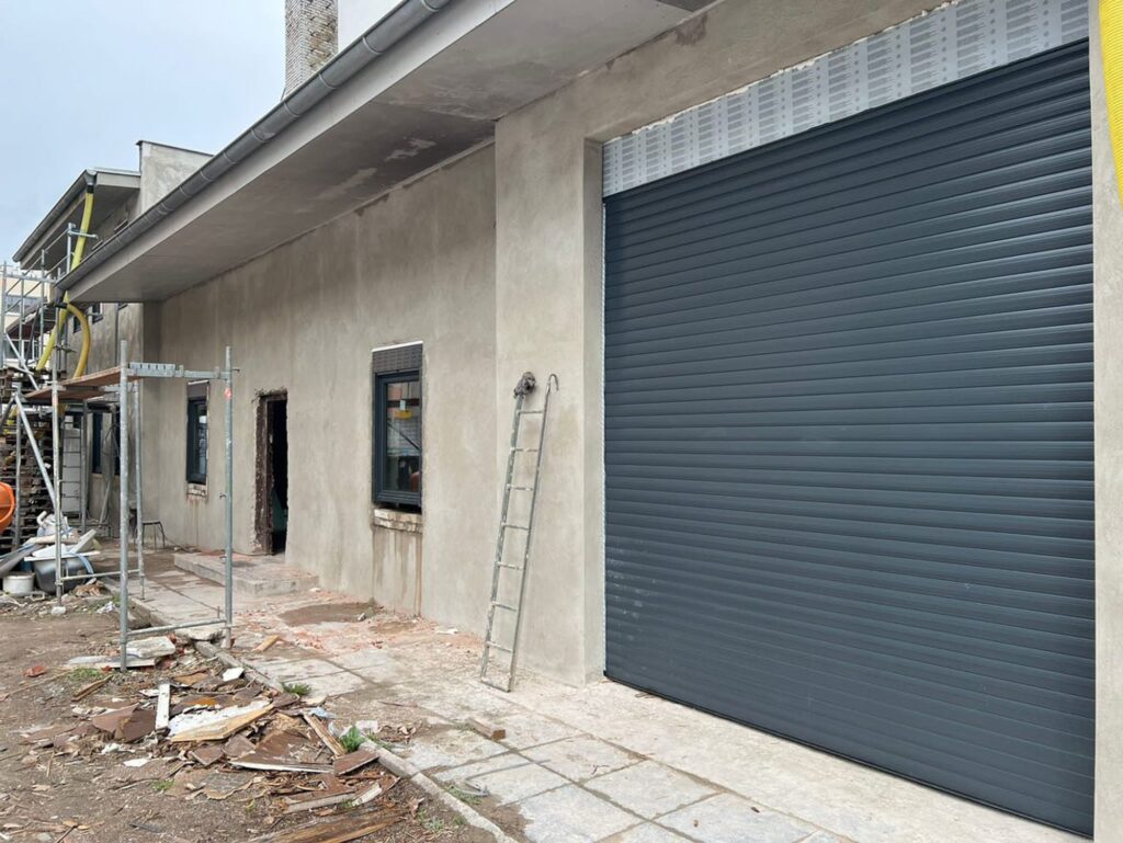 Frisch verputzte Fassade mit neuem Rolltor während der Sanierung in der Scheveninger Straße, Berlin-Neukölln