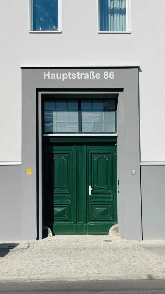 Grüne Haustür im grauen Putzportal am sanierten Wohnhaus Hauptstraße 86 in Berlin-Lichtenberg